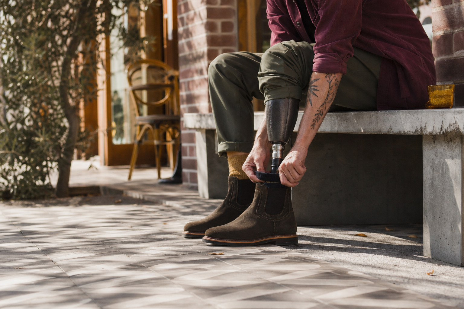 A person adjusting a boot around a below-knee prosthesis outside a cafe