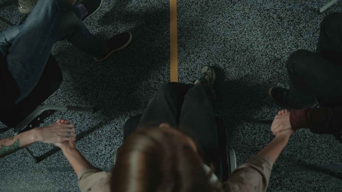 A diverse group of people holding hands in a circle, symbolizing support and unity in a mental health session.