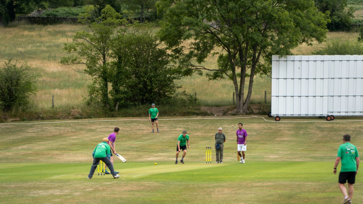 People are playing a game of cricket outdoors.