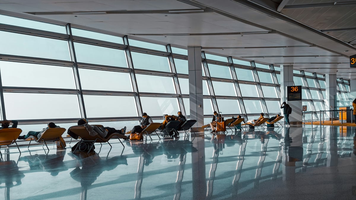 a group of people sitting in chairs in a large room with large windows