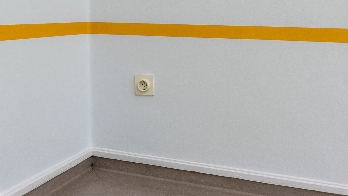 A clean wall with a yellow stripe and an electrical socket adds modern minimalist style.