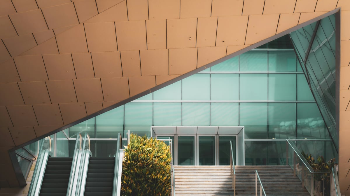 Modern building with glass entrance, stairs, and escalators.