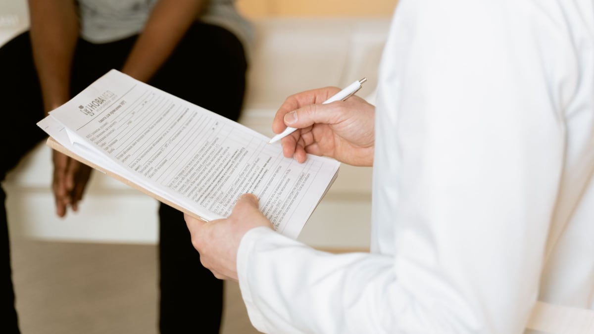 Healthcare professional reviews medical form during patient consultation in a clinic setting.