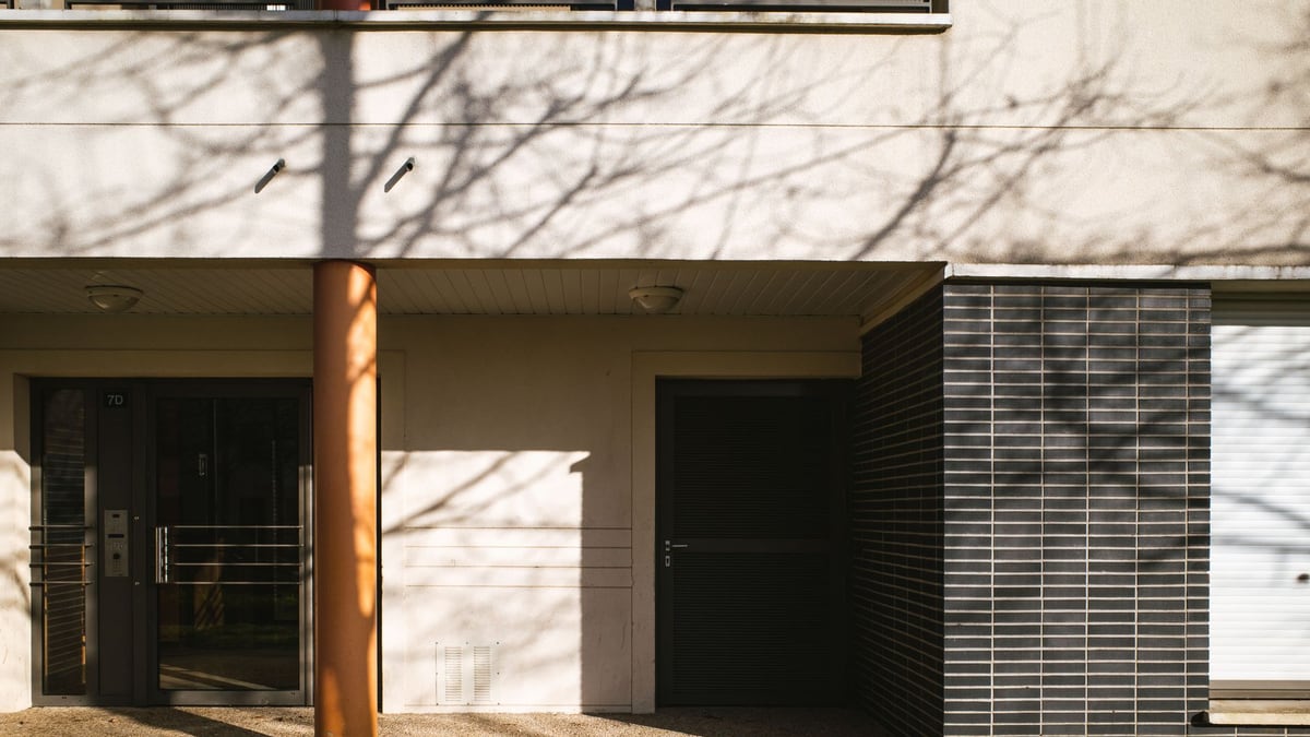 Entrance of a modern apartment building with distinctive shadows in Compiègne, Hauts-de-France, France.