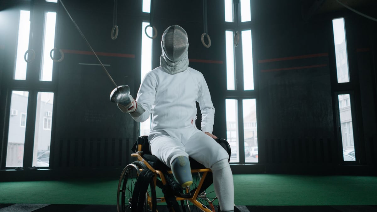 A fencer in protective gear practicing indoors, showcasing adaptive sports.