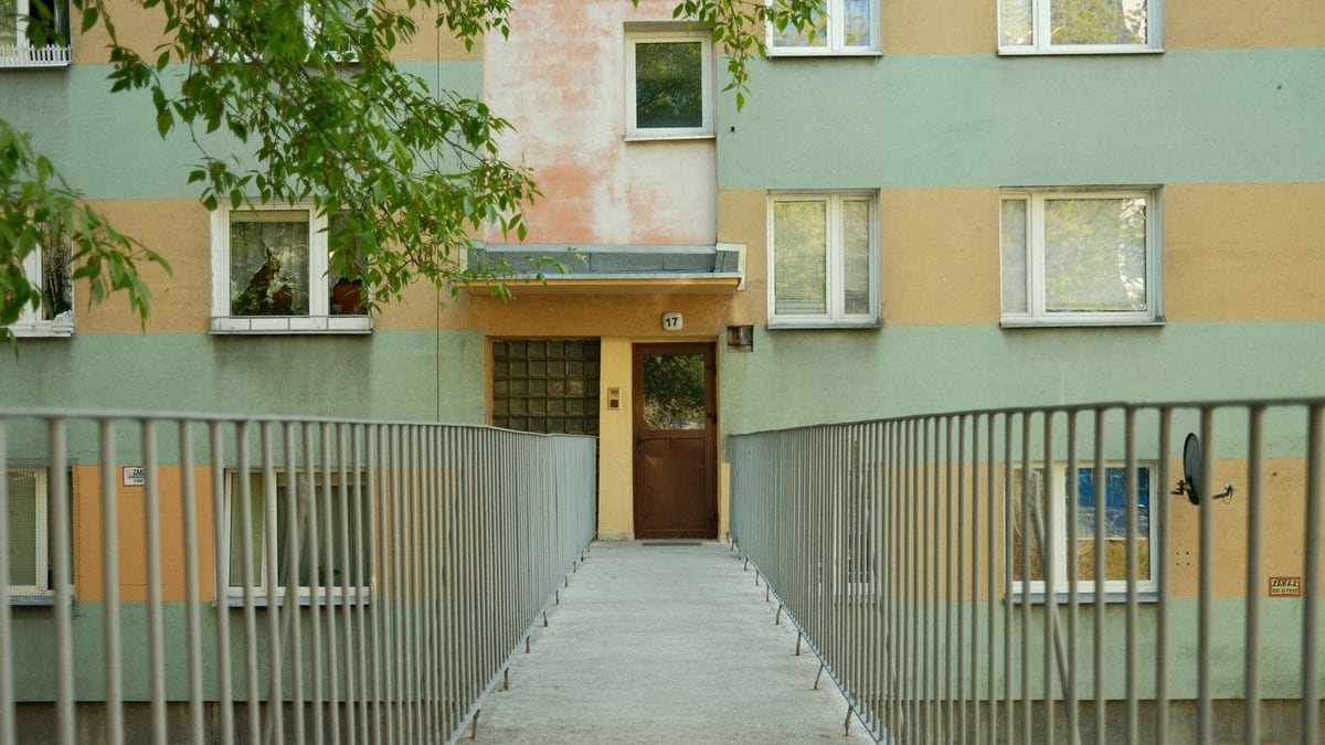 An inviting footpath leads to the entrance of a residential building on a sunny day.