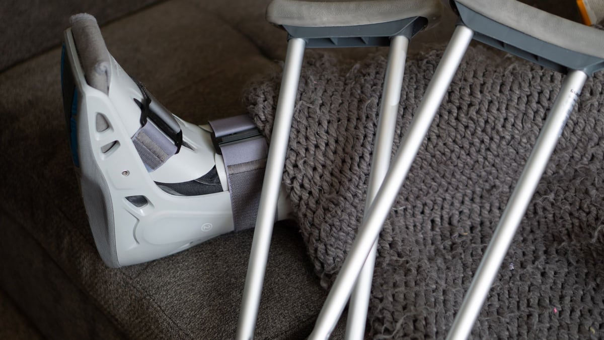 Close-up of an orthopedic boot and crutches on a couch, symbolizing injury recovery at home.